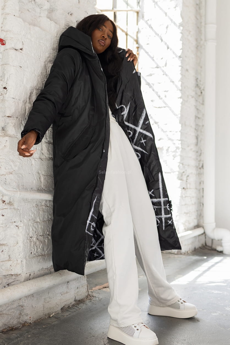 Długa dwustronna czarna kurtka XO polskiej firmy LaDonna. Zapinana na podwójny suwak. Posiada dwie klasyczne kieszenie i duży, obszerny kaptur. Materiał wyróżnia się ciekawym wzorem nadającym kurtce niepowtarzalny wygląd.