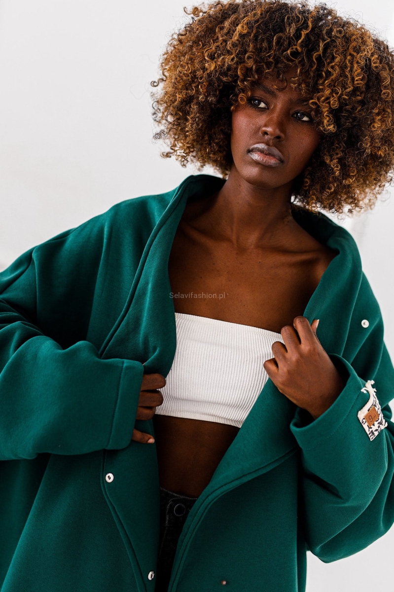 Długa bluza dzianinowa w kolorze zielonym o asymetrycznym kroju, zapinana na zatrzaski. Fason kimono ze stójką.