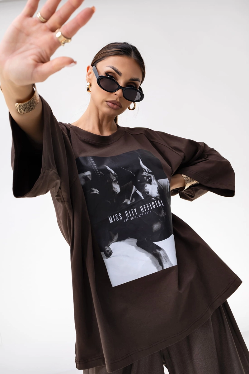 T-shirt Doberman o pudełkowym kroju posiada luźną, oversize’ową formę z przedłużonymi rękawkami do łokcia, co nadaje mu nowoczesny, sportowy wygląd. Duży nadruk, w formie grafiki stanowi główny element przyciągający uwagę.