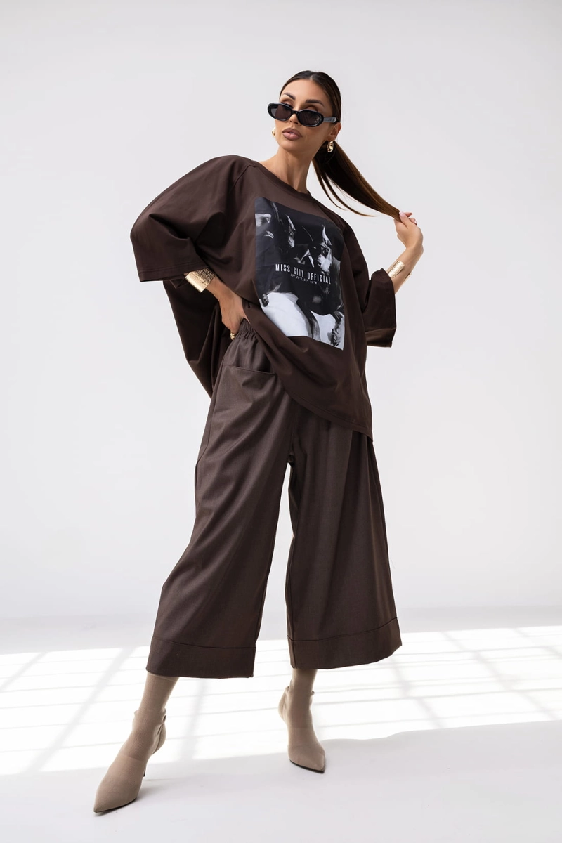 T-shirt Doberman o pudełkowym kroju posiada luźną, oversize’ową formę z przedłużonymi rękawkami do łokcia, co nadaje mu nowoczesny, sportowy wygląd. Duży nadruk, w formie grafiki stanowi główny element przyciągający uwagę.