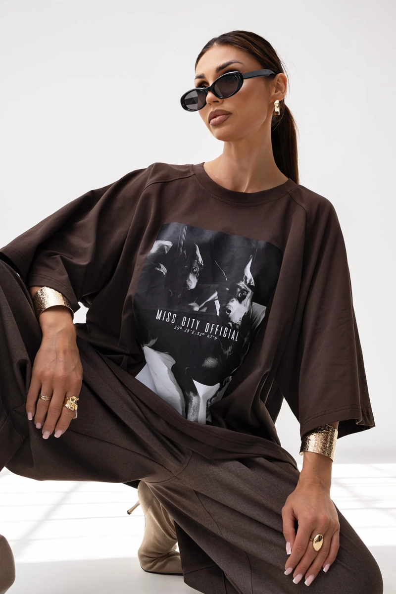 T-shirt Doberman o pudełkowym kroju posiada luźną, oversize’ową formę z przedłużonymi rękawkami do łokcia, co nadaje mu nowoczesny, sportowy wygląd. Duży nadruk, w formie grafiki stanowi główny element przyciągający uwagę.