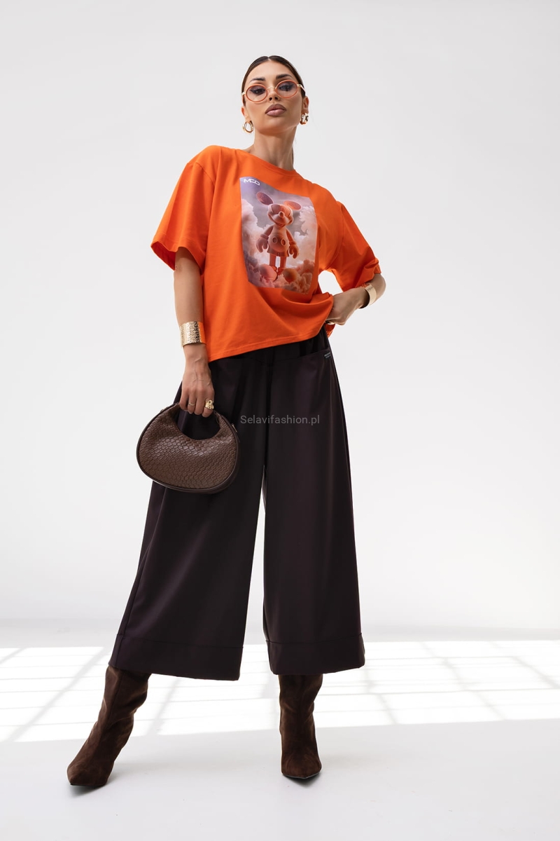 T-shirt Energy Miki ma luźny, oversize’owy krój i krótki rękaw. Wykonany jest z lekkiej bawełny. Na przodzie znajduje się duży nadruk – grafika w stylu 3D. Koszulka ma prosty fason, klasyczny dekolt pod szyję i pasuje zarówno do casualowych