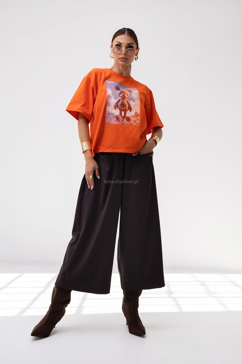 T-shirt Energy Miki ma luźny, oversize’owy krój i krótki rękaw. Wykonany jest z lekkiej bawełny. Na przodzie znajduje się duży nadruk – grafika w stylu 3D. Koszulka ma prosty fason, klasyczny dekolt pod szyję i pasuje zarówno do casualowych