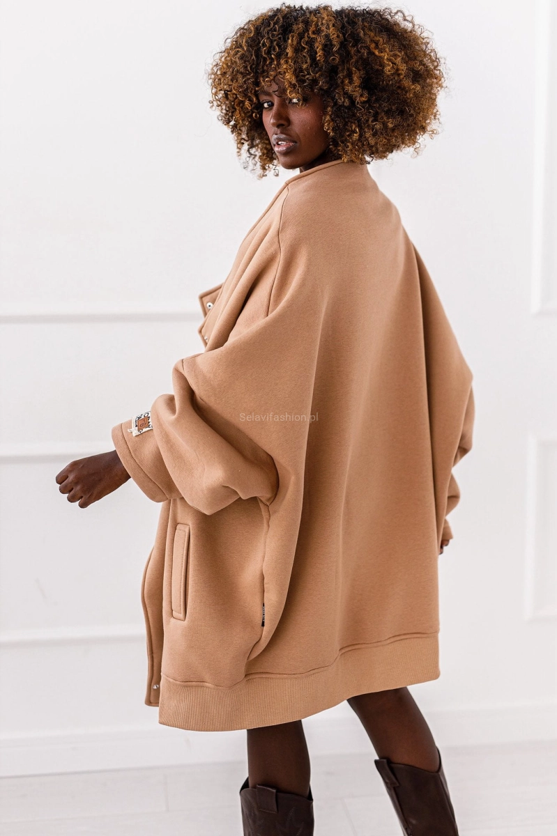 Długa bluza dzianinowa w kolorze beżowym o asymetrycznym kroju, zapinana na zatrzaski. Fason kimono ze stójką.